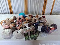 Full assortment of yarn rolls and knitting needles on a white cloth with a wood folding screen background.