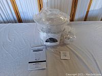 Full view of Cook's Essentials 3 tier digital steamer with clear stackable trays, digital base, and instruction manual on a table.