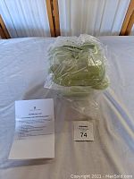 Set of three green gradient cast iron pepper-shaped pots tightly wrapped in clear plastic on white sheet.