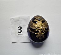 Front view of the cobalt blue egg showing the gold double-headed eagle and owner number card