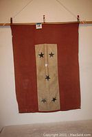 Full view of the red WWII fabric flag with a vertical white panel and five blue stars arranged in a cross pattern.