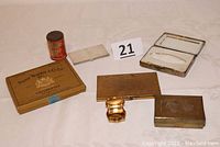 Seven assorted vintage cases and boxes displayed on a table, showing cigarette cases, smoking accessories, and card cases