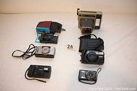 Photo showing all six cameras together with different sizes and styles visible, including cases for some cameras.