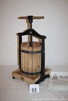 Full view of cast iron frame table model soft fruit press with wooden tub and base, showing screw and handle.