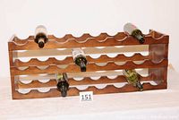 One wooden wine rack holding several wine bottles horizontally in the scalloped slots, showing bottle positioning.