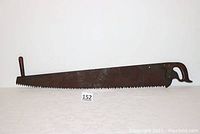 Full view of the 4-foot crosscut saw showing the entire metal blade with rust and unusual tooth pattern, wooden pistol grip handle, and secondary handle.