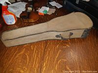 Aged beige canvas hard-sided violin carrying case, worn with use and discoloration.
