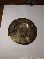 Top-down view of the round solid sterling silver ashtray showing four cigarette rests and surface wear.