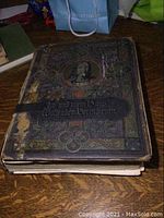 Book closed showing heavy age wear and taped binding from side view on wooden surface.