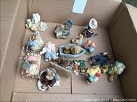 Photo showing a group of 15 bear figurines in a box, various styles, sizes and colors, some sitting, some standing, one lying on a boat.