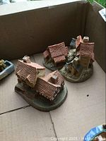 Boxed set showing three miniature David Winter village houses with detailed roofs and chimneys