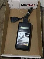 Front view of the Hypertech Power Programmer III device showing label, screen, and control buttons inside a cardboard box.