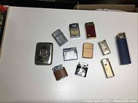 Top-down view of nine lighters and metal cigarette case arranged on white surface