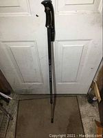 Full length photo of the black adjustable walking stick showing metal shaft, handle and rubber foot tip