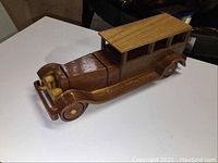 Side and front angled view showing the full handmade wooden car with detailed wood grain and wheel design.