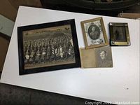 Overview of all four photos on white table surface showing large group photo, daguerreotype and two smaller portraits.
