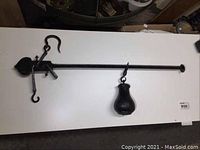 Full view of antique cast iron scale with attached counterweight on white surface.