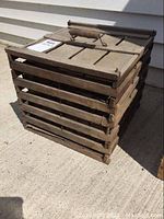 View of antique wooden egg crate with visible wood slats on the side and dusty weathered surface, wooden handle on top.