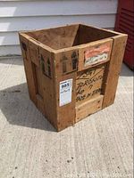 Front side view of the vintage wood crate showing handwritten markings, shipping label, and aged wear.