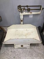 Front view of the scale showing the brass sliding weights and cast iron base.