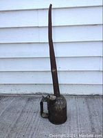 Front view of the large embossed CNR machine oiler showing the tall narrow spout and handle attached to the metal body with visible wear and dents.