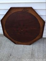 Front view of dark brown octagon crokinole board with visible natural wood grain and splits