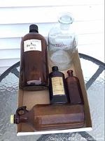 Box holding four brown glass bottles including a large Dettol bottle and a pale green decanter with stopper