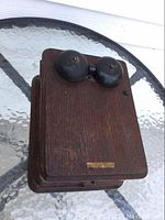 Top view showing two black metal bells mounted on an oak wooden box with visible wear and a small metal plaque.