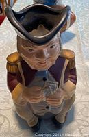 Ceramic decanter shaped as Abraham Whipple figurine wearing tricorn hat and holding cards