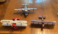 Three die cast metal airplanes arranged on a wooden surface, showing front and top views
