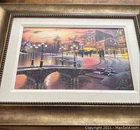 Framed winter night Paris city scene print featuring a stone arch bridge, buildings, lamp posts, and a sunset sky with reflections on water.