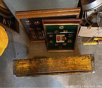 Image showing two framed pin displays leaning against a wall alongside a worn yellow vintage wooden Coca-Cola box lying horizontally on the ground