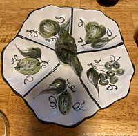 Top view of ceramic Italian relish dish with rooster handle and six compartments, decorated with green fruit and vine motifs