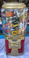Front view of the red and gold Seaga gumball machine filled with multiple Matchbox cars visible inside the transparent container