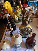 Wide view of nine assorted whiskey decanters on table showing various designs and materials