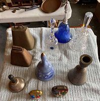 Photo showing all ten bells arranged on towel including metal cow bells, ceramic/porcelain blue Avon and Curry and Ives bells, crystal bells and smaller hand-painted bells.