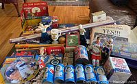 Wide view of sports collectibles including RC Cola cans, magazines, bobbleheads, and small collectibles on table and floor.