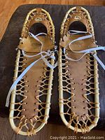 Full pair of Sherpa Snow Claw snowshoes showing brass frames and leather detail, laid flat