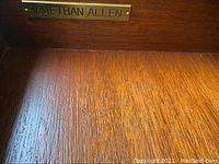 Close-up of Ethan Allen metal marking inside the drawer confirming brand authenticity.