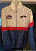 Front view of vintage racing jacket, showing multicolor red, white, and blue design with embroidered NASCAR Daytona 500 and STP logos on chest.