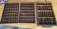 All three vintage wooden printers boxes displayed side by side on a wooden surface, showing compartments.