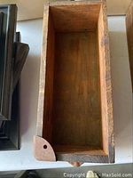Top view inside of a rectangular wooden drawer showing aged wood and metal reinforcements on corner.