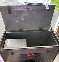 Open metal portable refrigerator showing inside interior with removable metal tray and lid hinges.