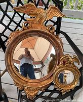 Front view of both mirrors displayed side by side showing size difference and eagle motifs