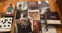 Photo showing multiple vinyl record albums spread out flat on a wood floor including identifiable Steve Martin album with bunny ears and other vintage music collections