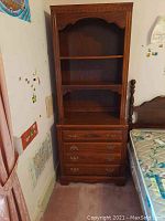 Front view of the complete two-piece wooden dresser with shelving showing four drawers and open shelves above under a decorative molded top.