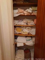 Full view of wooden shelves filled with folded bath towels and washcloths in assorted colors and sizes.