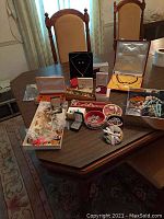 Wide shot of table with assorted costume jewelry, pins, earrings, necklaces, and jewelry boxes arranged.