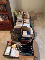 Wide view of boxes containing binders, photo albums, books, stationary and office paper supplies.