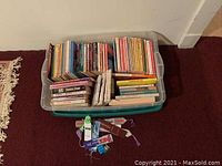 Box containing multiple softcover books including children's books and educational titles